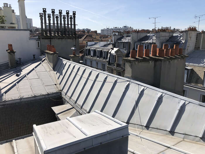 Toiture en zinc rénovée avec souches de cheminées sur un immeuble — VBS Bâtiment