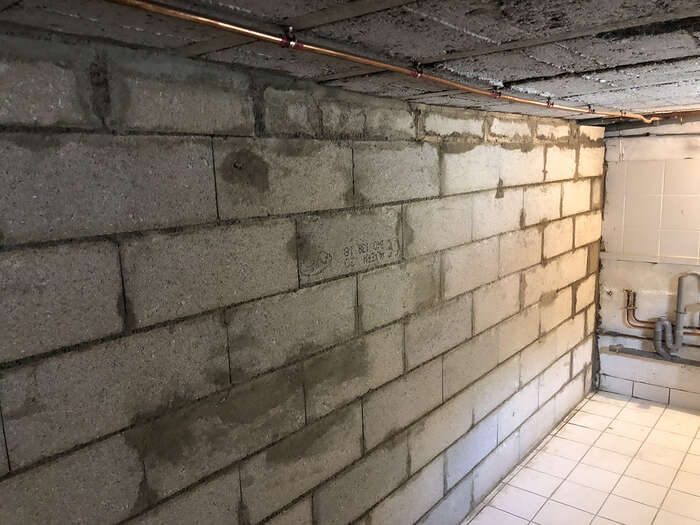 Mur en parpaings et réseau de plomberie dans un sous-sol en rénovation — VBS Bâtiment