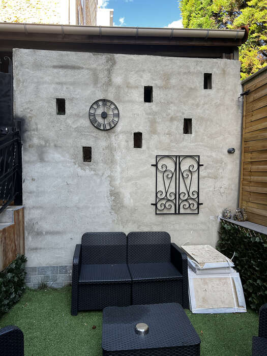 Cour extérieure aménagée : mur en béton décoratif, gazon synthétique et terrasse — VBS Bâtiment